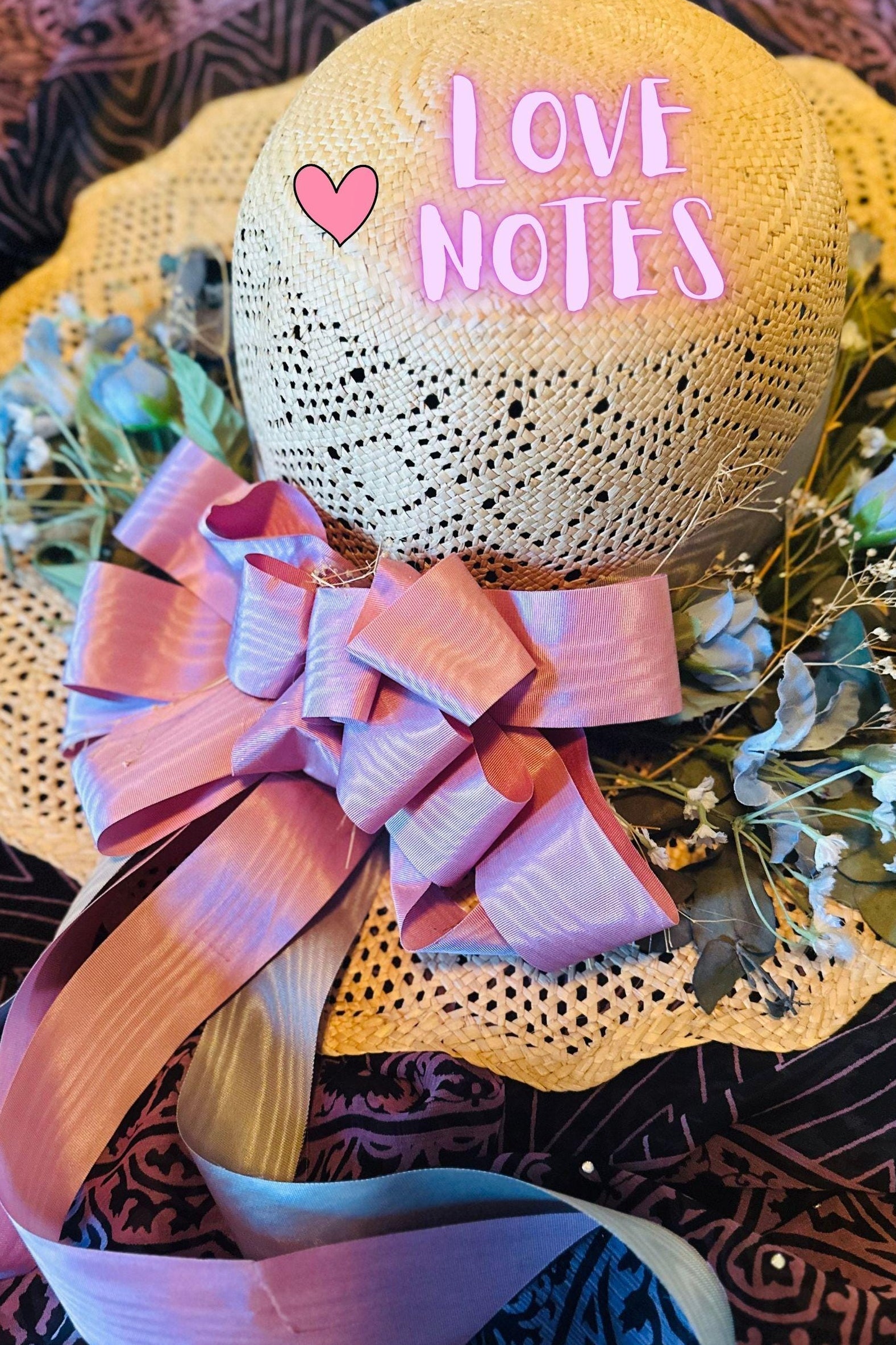 Decorative hat with 'LOVE NOTES' text and pink bow on a patterned background