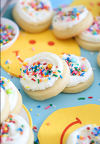 Cookies with white frosting and colorful sprinkles on a yellow and blue background